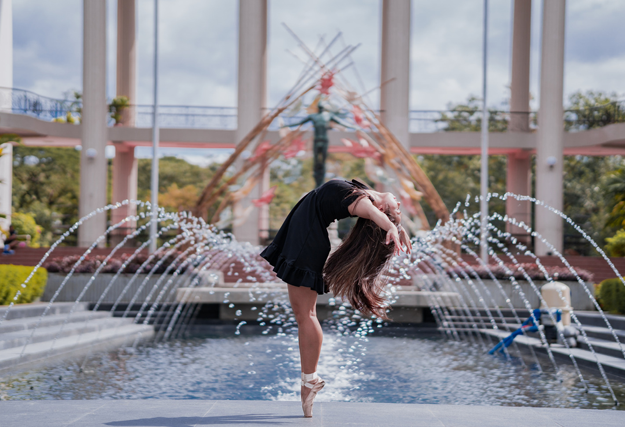 Comment devenir une femme fontaine ? Une femme se tient sur la pointe des pieds. Et des fontaines sont en arrière plan.