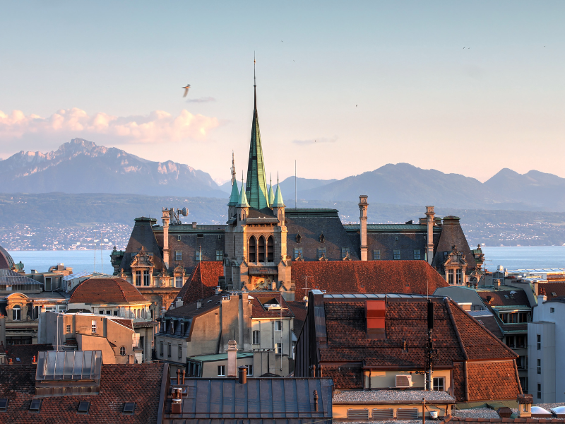 Vue panoramique sur les toits de Lausanne avec les montagnes et le lac Léman en arrière-plan.