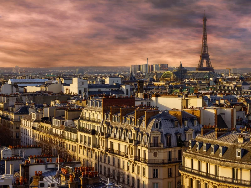 Massage érotique Paris - Vue panoramique de Paris au coucher du soleil avec la Tour Eiffel en arrière-plan sous un ciel dramatique.