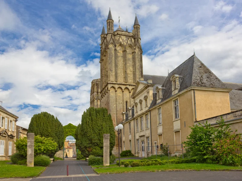 Massage érotique Poitiers - Vue de l'église Notre-Dame-la-Grande à Poitiers avec ses arbres environnants et un ciel partiellement nuageux.