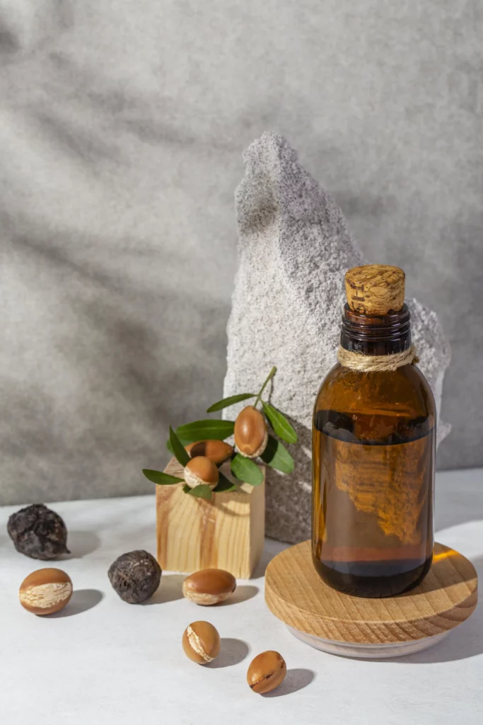 Bouteille d'huile de massage avec des noix d'argan posées à côté, sur un fond naturel et apaisant.