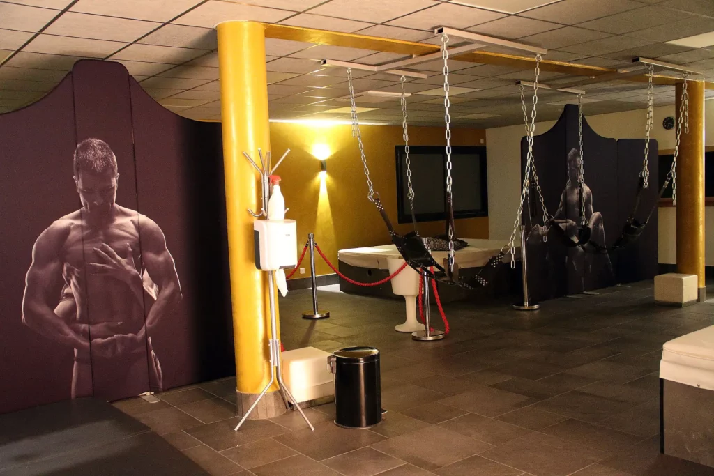 Espace coquin des Jardins de Bao avec balançoires, lit et cloisons décorées, près d’Aix-les-Bains